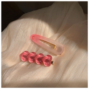 Detailansicht der rosa Harz-Herzhaarklammern und Tropfen-Clip auf Satinstoff