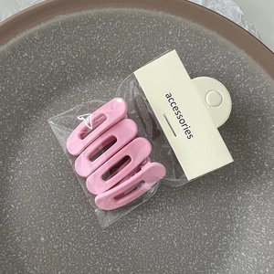 Vue détaillée de quatre pinces à cheveux roses mates sur une assiette pour le coiffage