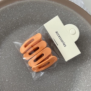 Lot de quatre pinces à cheveux orange mat avec design ovale ajouré en emballage
