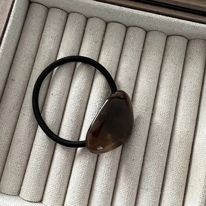 Detail of dark brown translucent pea-shaped resin charm on black elastic hair tie