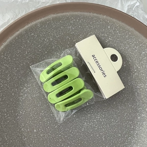 Lot de quatre barrettes en plastique vert mat sous emballage avec carte de support