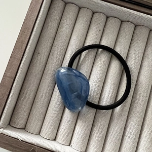 Detailed macro view of the minimalist blue marble texture acrylic bead on a black hair tie