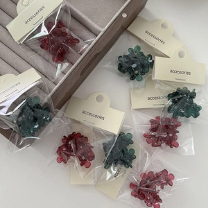 Détail de mini pinces à cheveux fleur mat en rouge foncé et vert avec emballage
