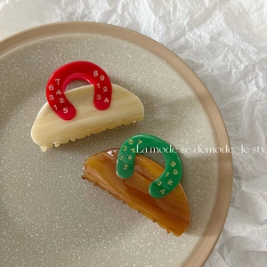 Detail of retro hair claw clips in red and green color block with gold numeric accents