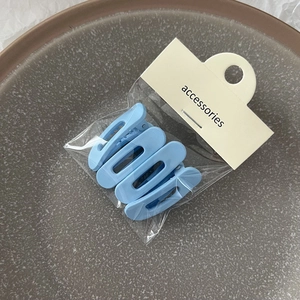 Lot de quatre barrettes bleu ciel mat dans un emballage avec carte de présentation
