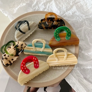 Set of seven retro leopard and marble pattern hair claw clips on a white ceramic plate