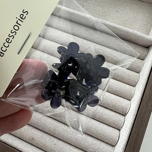 Détail de quatre mini pinces à cheveux en forme de fleur avec ressorts dans l'emballage