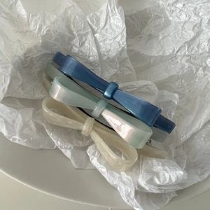 Three elegant acetate bow hair clips in navy, pearlescent green and white colors