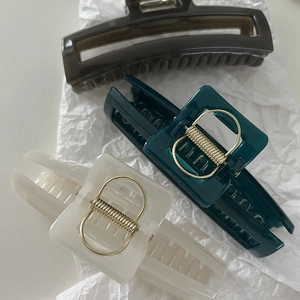 Close-up of rectangle hair claw clips in dark brown, emerald green, and cream white
