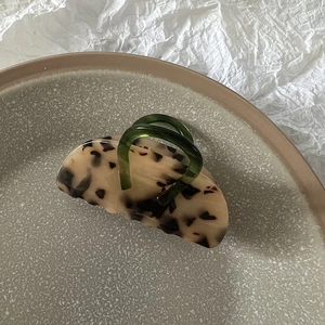 Macro shot of stylish leopard print hair claw clip with emerald green handle detail