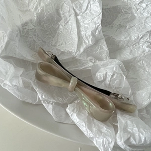 Macro view of cream white acetate bow hair clip with mother-of-pearl marble texture