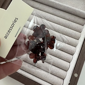 Détail de mini pinces à cheveux fleur en résine ambrée présentées sur carte support