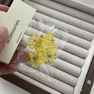 Vue détaillée des mini pinces à cheveux fleurs jaunes dans un emballage transparent