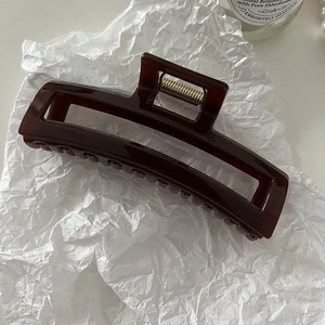 Detailed view of dark brown hollow rectangular hair claw clip with golden metal spring