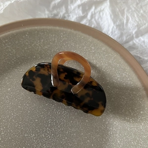 Macro detail of tortoiseshell leopard print hair claw clip on a minimal ceramic plate