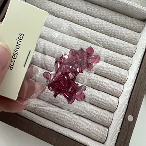 Détail de 4 mini pinces à cheveux à fleurs rose foncé translucides sous emballage