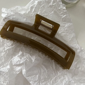 Detail of translucent olive green rectangular hair claw clip with golden metal spring