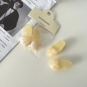 Vue détaillée des pinces à cheveux jaune crème avec cœurs marbrés sur carte