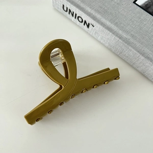 Close-up of olive green acetate hair claw clip with crossed loop and metal spring mechanism
