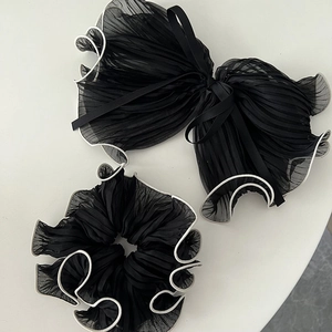 Detail of black pleated mesh hair scrunchie and large bow clip with white contrast edging