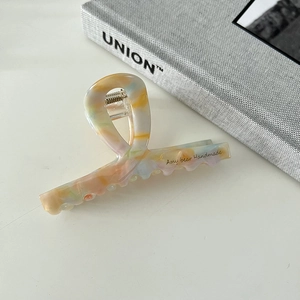 Detail of elegant acetate hair claw clip with colorful marble pattern and metal spring