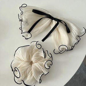 Detail of white pleated organza bow clip and scrunchie with contrast black edges