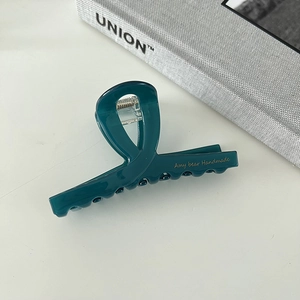 Detail view of a dark green acetate shark hair claw clip with a strong metal spring mechanism