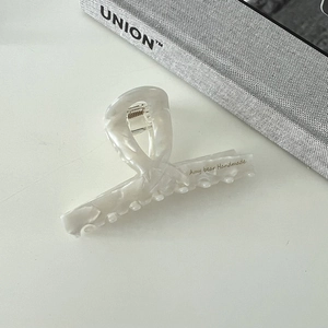 Detail showing the pearlescent texture and twisted design of this elegant acetate hair claw