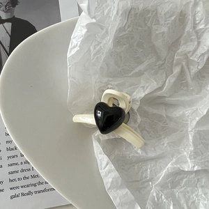 Détail d'une mini pince à cheveux blanc crème ornée d'un cœur noir brillant sur porcelaine