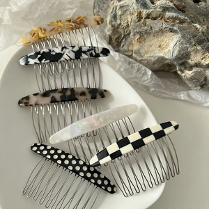 Vue détaillée des peignes à cheveux avec motifs marbrés et damiers en acétate sur métal