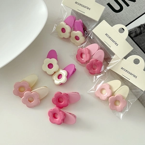 Set aus niedlichen mattierten Harz-Blumen-Haarspangen in Rosa und Weiß auf dem Tisch