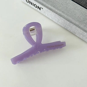 Detail showing elegant purple hair claw clip with golden handmade lettering and metal spring