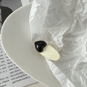 Vue détaillée d'une pince à cheveux crème avec un cœur noir sur un plateau en céramique