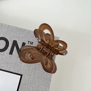 Detailed close-up of butterfly hair claw clip in amber translucent frosted acrylic