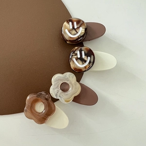 Brown and cream floral smiley hair clip set on a leather and white textured surface