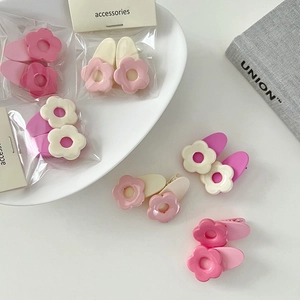 Nahaufnahme süßer Blumen-Haarspangen in pastellrosa und weißem mattem Finish auf Tablett
