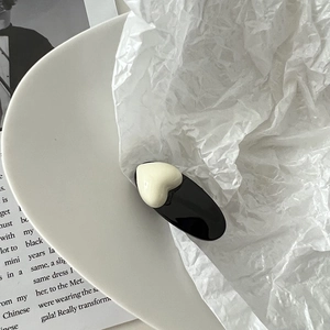 Détail de la pince à cheveux ovale noire minimaliste avec cœur crème sur céramique