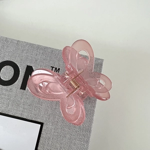 Detail view of pink butterfly hair claw clip with translucent jelly texture and gold spring