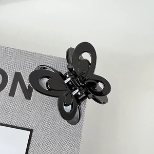 Close-up of a polished black butterfly hair claw clip with a glossy finish and metal spring