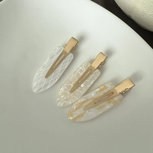 Detail view of acetate seamless hair clips with marble patterns and gold plating