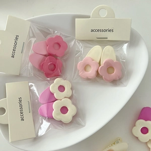 Detail von blumenförmigen Harz-Haarspangen in Rosa und Weiß in der Zubehörverpackung