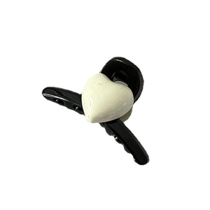 Pince à cheveux noire minimaliste avec décor de cœur crème doux sur fond blanc pur