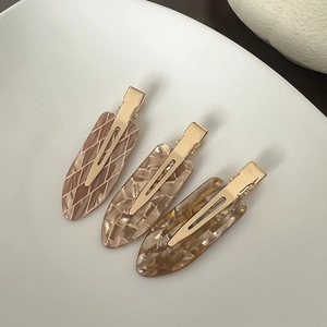Close-up of three acetate hair clips with marble patterns and gold metal base