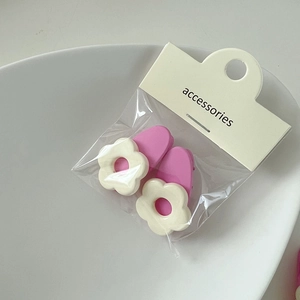 Detail von süßen weißen Blumen-Haarspangen auf rosa Basis mit Kartenverpackung auf Keramik