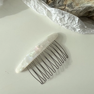Détail d'un peigne à cheveux en résine motif marbre avec des dents métalliques argentées