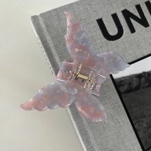 Detailed close-up of marble pink and blue butterfly hair claw clip with golden metal spring