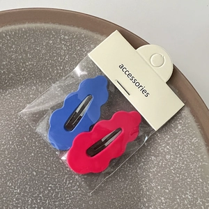 Détail de barrettes à cheveux ondulées bleu et rose avec emballage de vente sur assiette
