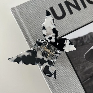 Detail of butterfly hair claw with black and white marble acetate texture and gold spring