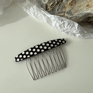 Détail d'un peigne à cheveux rétro à pois noirs et blancs avec dix dents argentées
