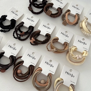 Detailed view of elastic earth-tone hair bands with charms on white display cards